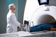 © Roman - Senior Radiologist Controls MRI or CT or PET Scan with Male Patient Undergoing Procedure. High-Tech Modern Medical Equipment. Friendly Doctor Working With Patient