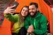 Happy couple taking selfie near tent