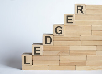 Three wooden cubes with letters LEDGER on white table.