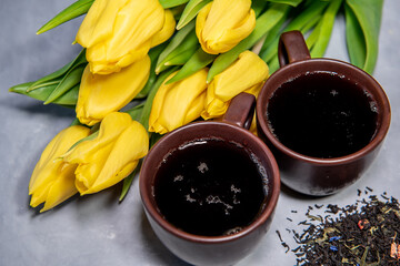 Two cups with tea and dried tea leaves on a gray background. Close-up. Place for text