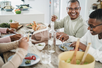 Wall Mural - Happy black family eating lunch at home - Father, daughter, son and mother having fun together sitting at dinner table - Main focus on man face