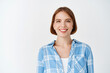 © Cookie Studio - Smiling candid woman in casual clothes looking happy. Young girl with short hair and light make-up standing on white background