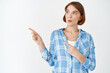© Cookie Studio - Wow, look. Excited cute girl with natural facial skin, whistle intrigued, pointing and gazing left at copy space, checking out advertisement, white background