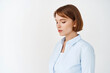© Cookie Studio - Portrait of young natural girl with short hair, wearing blue blouse, looking down and sideways, standing on white background for your logo