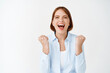 © Cookie Studio - Yes I did it. Happy and satisfied lucky woman winning, making fist pump and shouting with joy, celebrating victory or success, triumphing on white background