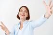 © Cookie Studio - Happy beautiful woman stretch out hands for hug and smiling with love, standing on white background in casual blouse