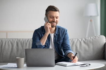 Wall Mural - Smiling bearded man having phone conversation with colleagues from home