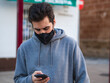 © David Martínez - Hombre joven con mascarilla usando su móvil