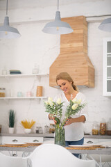 Wall Mural - Pretty housewife putting beautiful flowers into the vase