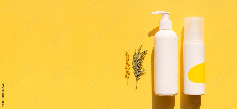 Clean white cosmetic containers bottles with mimosa flowers on yellow background flat lay top view. Blank label package for branding mock-up. Spring cosmetics concept. Natural organic beauty product - obrazy, fototapety, plakaty 