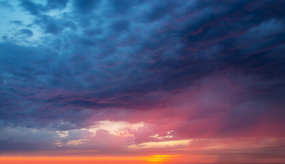 Colorful dramatic dark stomy sky with clouds at sunset, nature background