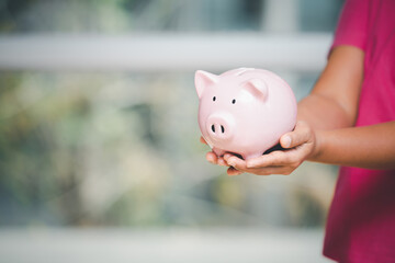 Woman hand holding pink piggy bank for saving money prepare financial management in the future, concept business saving money and investment growth professional.