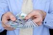 © Oleg - US dollars in male hands close up, man in business clothes counts the money. Concept of bribe, salary, bonus or loan