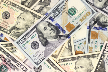 one hundred dollar bill lies on scattered dollar bills of different denominations