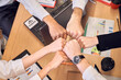 © Roman - Top view of cheerful business team keeping fists together as a symbol of unity while working together in the modern office