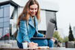 © Тарас Нагирняк - Happy woman working remotely, on a bench in the middle of the city, lifestyle, urban lifestyle, freelancer