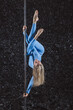Woman athlete blonde in a blue suit on a pylon on a black background
