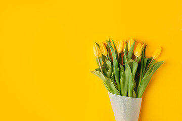 Wall Mural - Yellow tulip flowers bouquet on yellow background. Flat lay, top view, copy space. Banner for seasonal holiday, springtime concept, International Woman day, 8 march, Happy Easter greeting card