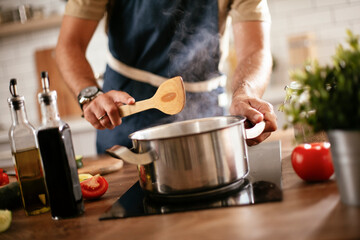 Wall Mural - Handsome man preparing pasta in the kitchen. Guy cooking a tasty meal..