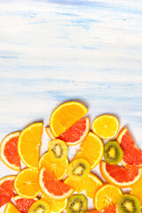 Sticker - Vertical shot of fresh orange, grapefruit and kiwi slices isolated on the white-blue background