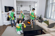 © sofiko14 - Male and female cleaners in green apron and gloves using modern tools for cleaning bright apartment. Team on mixed race people tidying up customer house.