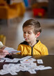 little boy learns words from cards under the ABA therapy program at home at the table