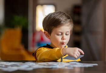 Sticker - little boy learns words from cards under the ABA therapy program at home at the table