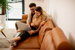 © BGStock72 - Young couple using laptop together while sitting on sofa at home