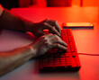 © Albert Morcillo/ADDICTIVE STOCK - Crop anonymous male typing on keyboard while working on computer and sitting at desk with smartphone in dark room