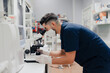© Alberto Ortega/ADDICTIVE STOCK - Side view of crop anonymous male medic in uniform and mask using microscope while working in lab