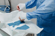© Alberto Ortega/ADDICTIVE STOCK - Crop view of anonymous young male veterinarian in sterile uniform putting on elastic gloves while preparing for surgery in operating room