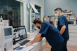 © Alberto Ortega/ADDICTIVE STOCK - Anonymous young male doctors in respiratory masks and uniforms working on desktop computer in clinic