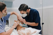 © Alberto Ortega/ADDICTIVE STOCK - Crop anonymous male veterinarian with nurse in uniforms treating animal patient on table in hospital