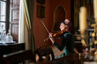 © Almudena Cuenca/ADDICTIVE STOCK - Side view of cheerful female musician touching hair while sitting on armchair in vintage styled room during violin rehearsal