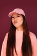 © Victor Torres/ADDICTIVE STOCK - Portrait of happy young asian woman in the studio wearing pink clothes over garnet background