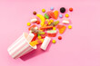 © Andres Victorero/ADDICTIVE STOCK - Top view of assorted multicolored sweet jelly candies and marshmallows scattered near disposable striped cup on pink background