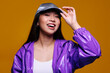© Victor Torres/ADDICTIVE STOCK - Portrait of happy Asian young woman. She wears a purple jacket and a grey cap and is looking at camera smiling against a yellow background