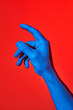 © Angela Rober/ADDICTIVE STOCK - Man's blue hand pointing upwards over red background. Isolated vertical photo