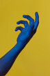 © Angela Rober/ADDICTIVE STOCK - Man's blue hand holding something invisible over yellow background. Isolated vertical photo