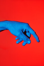 Man's Blue Finger Pointing Downwards Over Red Background. Isolated Vertical Photo