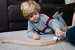 © Angel Santamaria/ADDICTIVE STOCK - Cute little boy lying on carpet and playing with toy car in living room at home