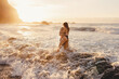 © Carlos Pintau/ADDICTIVE STOCK - Full length side view unrecognizable cheerful young couple standing embracing each other on waving sea water while spending sunset time on the beach of Tenerife island