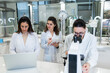 © Carlos Pintau/ADDICTIVE STOCK - Group of professional female scientists using microscope and laptop while conducting research together in modern lab
