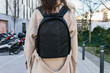 © David Munoz/ADDICTIVE STOCK - Back view unrecognizable female in warm coat carrying black backpack strolling on urban city street