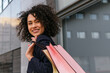 © David Munoz/ADDICTIVE STOCK - Side view of satisfied African American female with paper bags standing on street after shopping and looking away