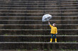 © Egoitz Bengoetxea/ADDICTIVE STOCK - Kid in yellow raincoat and rubber boots playing under umbrella along stone steps on rainy day in city