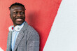 © David Munoz/ADDICTIVE STOCK - Young positive black male manager in formal clothes with modern wireless headset looking away near bright wall in town