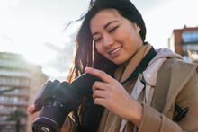 Ethnic Young Happy Asian Female Photographer Shooting Photo On Professional Photo Camera On City Street