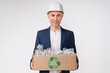 Middle-aged cheerful caucasian engineer holding a box full of plastic bottles for recycling isolated over white background