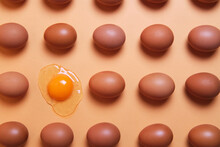 From Above Of Pattern Of Whole Brown Eggs Placed In Even Rows With Raw Eggs On Peach Table In Studio